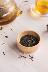 Dry tea in bowl, on wooden background