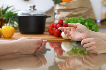 Close-up of human hands are gesticulate over a table in the kitchen. Women choosing menu or making online shopping. So much ideas for tasty cooking