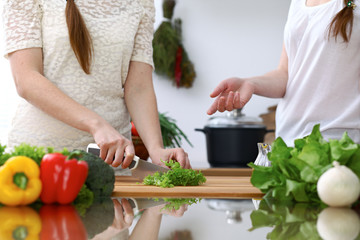 Close-up of  human hands  cooking in a kitchen. Friends having fun while preparing fresh salad. Vegetarian, healthy meal and friendship concept
