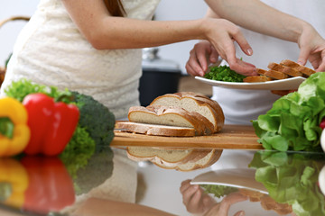 Close-up of human hands slicing bread in a kitchen. Friends having fun while cooking in the kitchen. Chef cook represent culinary masterclass