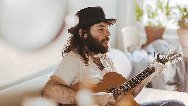 Talented soulful musician strums his guitar as he relaxes at home