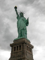 Statue of liberty seen from the front with a grey and cloudy sky as background in Manhattan, New York City..