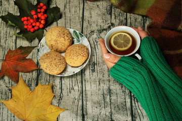 Tea with lemon, cookies, autumn leaves and hands