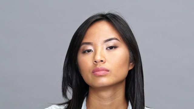 Young serious asian concentrated woman isolated looking camera
