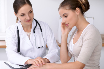 Doctor reassuring her female patient while  sitting at the desk. Medicine, help and health care concept
