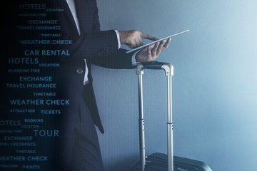 Travel Concept, Graphic about Travel Technology on Modern Businessman wearing suit and touching a digital tablet at grey wall in the airport, Side view