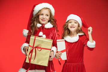 Two happy girls in santa claus hats with gift boxes