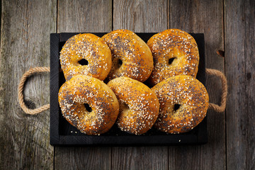 Bagels in a ceramic old bowl with a textile napkin on a light stone or concrete background. Selective focus. Top view. Copy space. Square image.