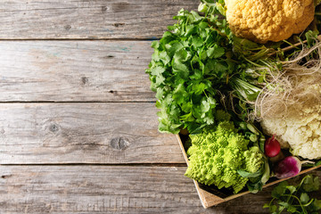 Variety of fresh raw organic colorful cauliflower, cabbage romanesco and radish with bundle of...