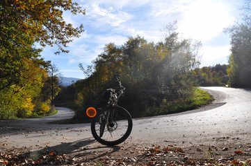 Bicycle on road on bend under a mountain. Cycle on the road on sunny autumn day