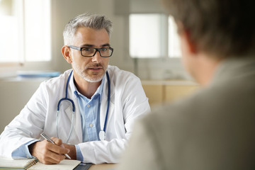 Doctor talking to patient in office - obrazy, fototapety, plakaty