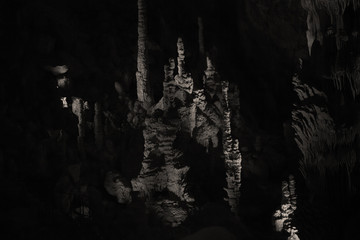 Spéléologie dans une grotte avec stalagmites et stalagmites dans la pénombre dans une salle cathédrale d'une caverne.