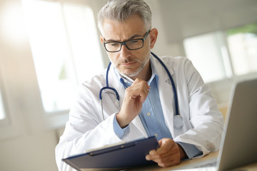Doctor in office working on patient file