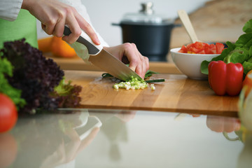 Closeup of human hands cooking vegetables salad in kitchen on the glass  table with reflection