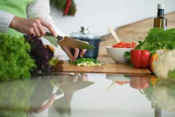 Closeup of human hands cooking vegetables salad in kitchen on the glass  table with reflection