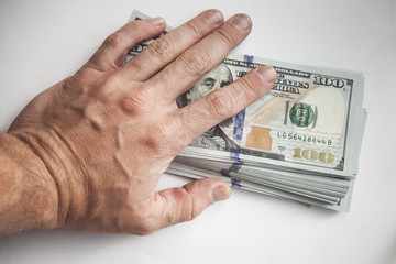 Male hand covers a bundle of US Dollars