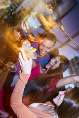Group of friends partying in a nightclub and toasting drinks