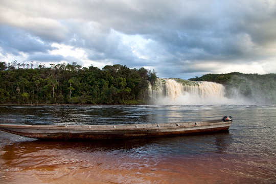Wooden Boat nearby Gorgeous Waterfall
