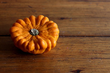 Funny decorative pumpkin flower close up on wooden background, halloween texture