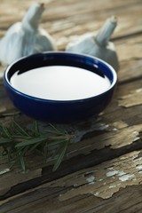Garlic bulbs, rosemary and oil on wooden table
