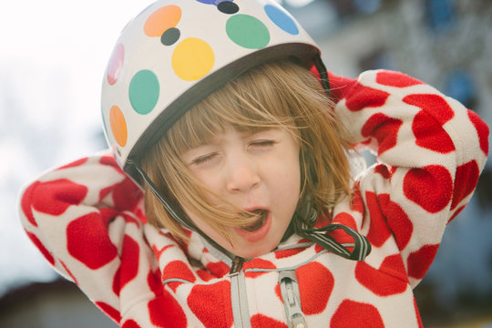 a girl with a polka-dotted helmet and jacket makes a funny face for the camera