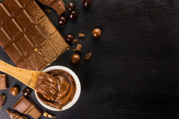 frame with different types of chocolate, powder, cream and bar on a dark background, with space to place texts or logos on the right side