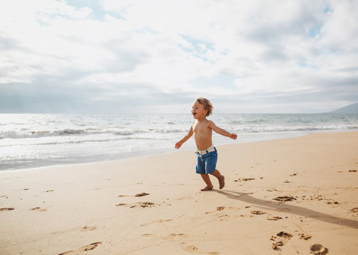 Toddler boy running on sandy tropical beach alone