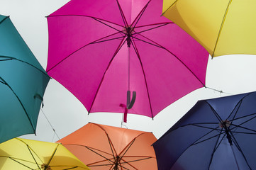 Hanging multicolored umbrellas over blue sky. Abstract background