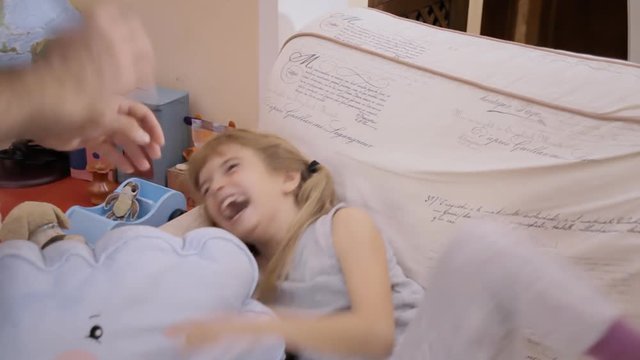 A dad tickling his daughter on the sofa. Bonding, happy family, fun times.
