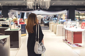 Fototapeta na wymiar Young asian woman walking in cosmetics department at the mall