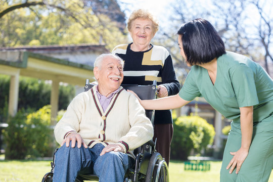 Two active elderly people outdoor with asian nurse