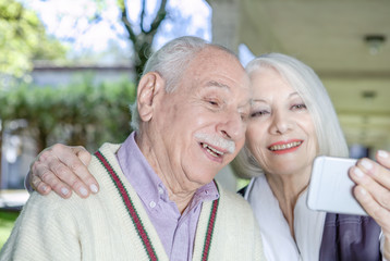 Active elderly couple outdoor using mobile phone