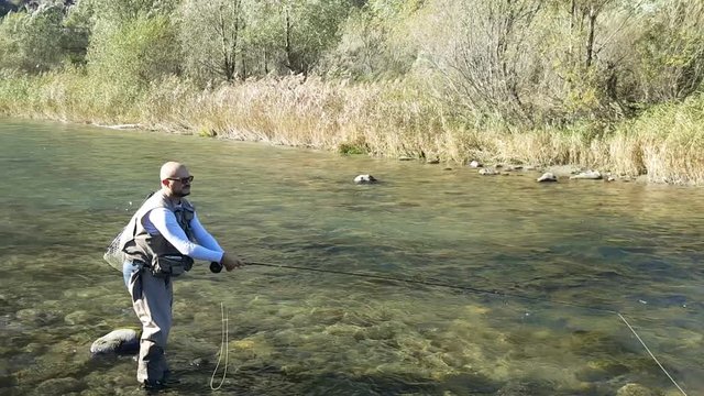 pescatore sul fiume con canna da pesca a mosca