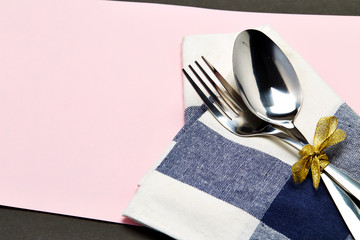 silver spoon and white napkin on pink with gray background