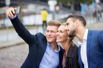 three businesspeople taking a selfie and smiling