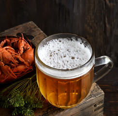 Glass of beer and a boiled crayfishes in a plate on a wooden background