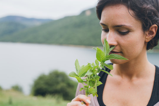 Beautiful woman smelling fresh herbs in front of a lake