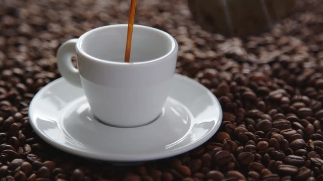 Pouring cup of hot coffee and roasted coffee beans on the table