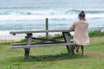 Fototapeta premium Woman relaxing on a bench, back view