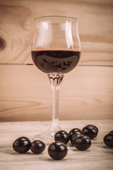 Glass of red wine and grapes on rustic wood table