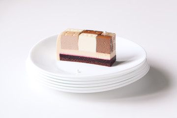 Piece of Contemporary Three Chocolates Mousse Cake on white plate, on white background.