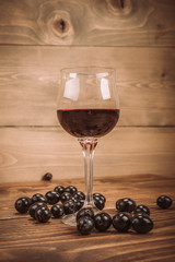 Glass of red wine and grapes on rustic wood table