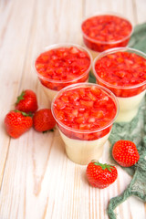 Tasty strawberry mousse pudding or panna cota in glass on wooden table