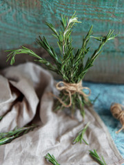 A bunch of fresh rosemary on linen cloth, Rustic greenery on wooden background.