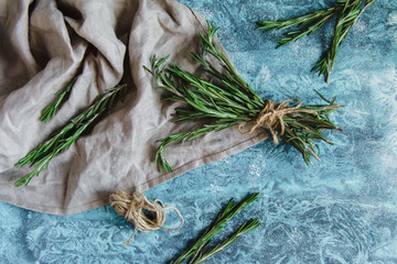 Overhead still life. A bunch of fresh rosemary on linen cloth, Rustic greenery on wooden background.
