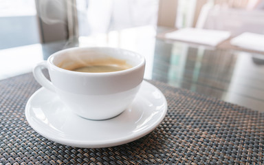 white cup of hot coffee on table with morning sunrise