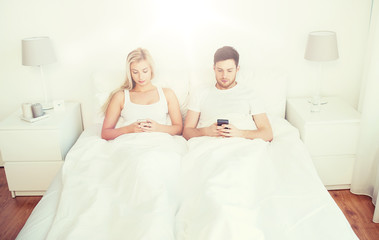 Obraz na płótnie Canvas couple with smartphones in bed