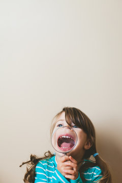 Girl holds magnifying glass - looks like she is missing a nose