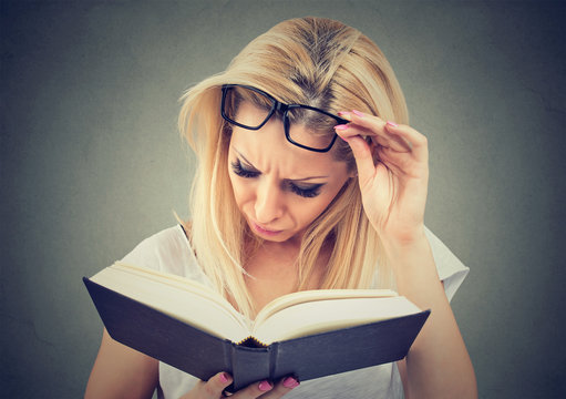 Young woman with glasses suffering from eyestrain after reading a book