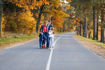 A happy family having fun in autumn forest. family with children walking in the park. Mother and father with son and daughter resting and hugging outdoors in fall with 